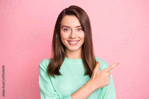 Photo of charming young girl indicate forefinger empty space wear turquoise pullover isolated pink color background