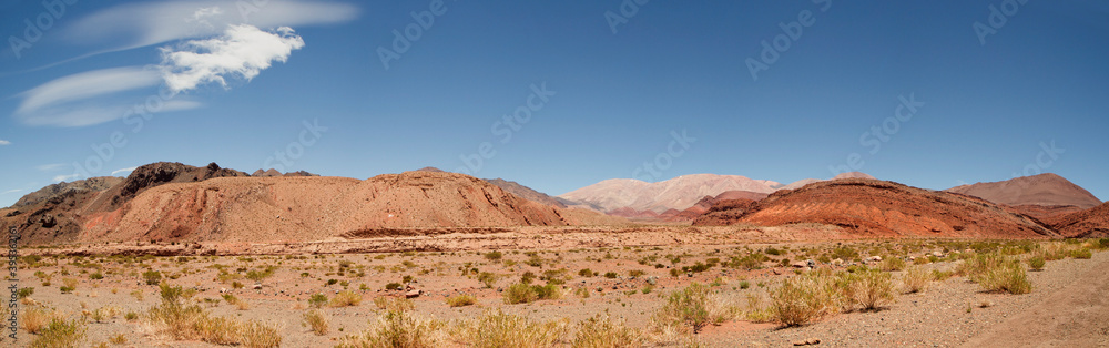 Desert landscape. View of the arid valley, red sand, sandstone formations and mountains under a deep blue sky. 