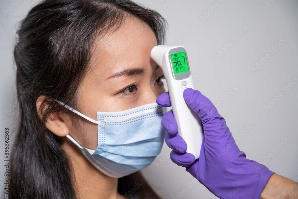 Mesure de température inférieure à 37 degrés celsius au front d'une jeune femme asiatique. Mesure de température inférieure à 37 degrés celsius au front d'une jeune femme asiatique.