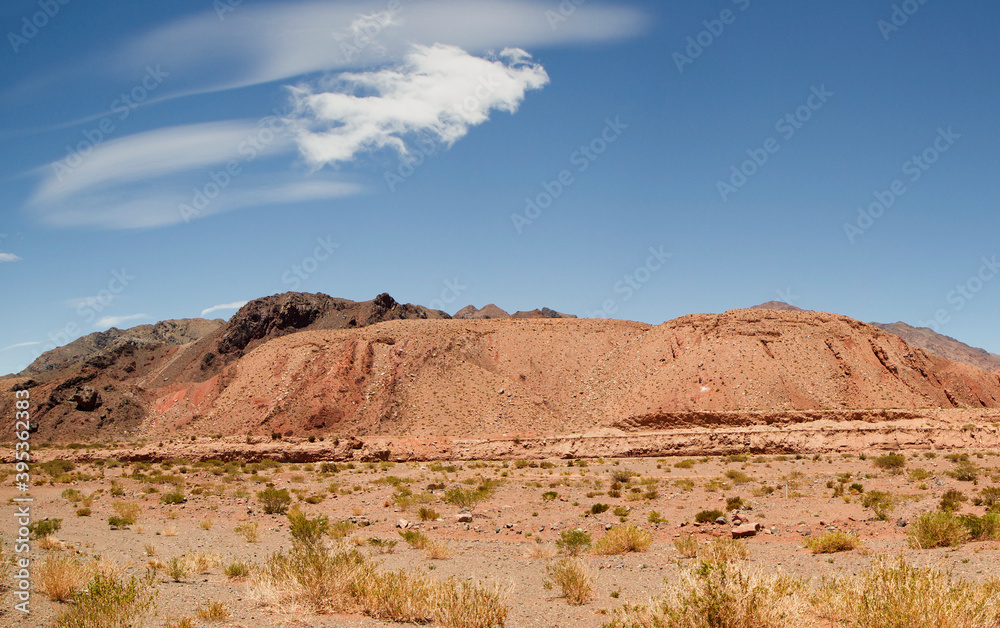 Desert landscape. View of the arid valley, red sand, sandstone formations and mountains under a beautiful blue sky. Desert landscape. View of the arid valley, red sand, sandstone formations and mountains under a beautiful blue sky.