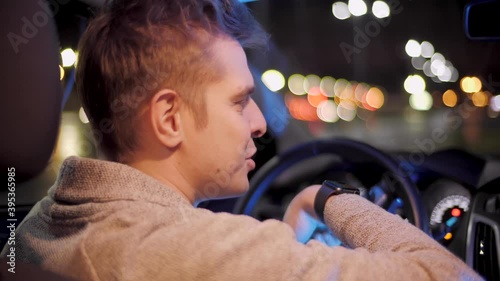 Happy driver using smartwatch in a car for handsfree voice recorder recognition audio message command late night. creative man with smartwatch using voice command recorder