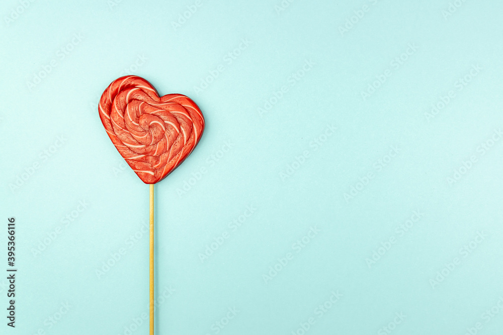 Heart shaped lollipop for Valentine's Day on light blu copy space background.