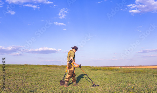 Man with a metal detector and a shovel looking for treasure