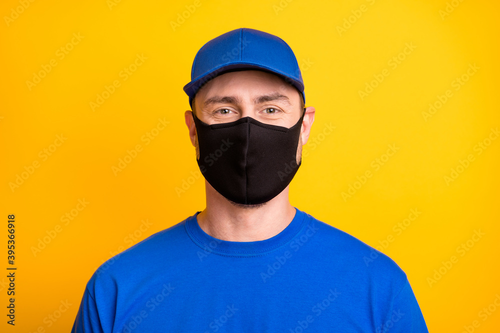 Portrait of deliveryman look camera headwear medical cold safety black mask isolated on yellow color background Portrait of deliveryman look camera headwear medical cold safety black mask isolated on yellow color background