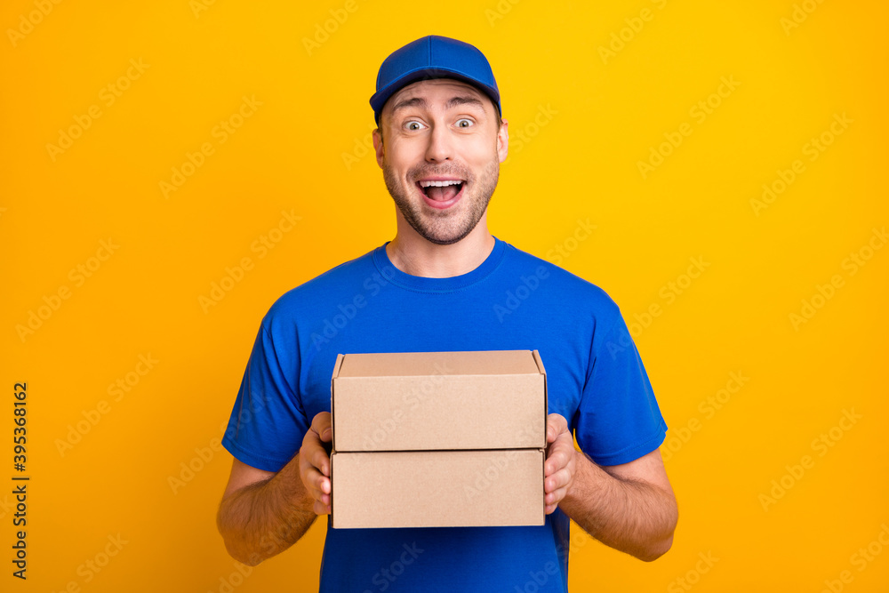Photo of impressed friendly guy hands hold package open mouth smile isolated on yellow color background Photo of impressed friendly guy hands hold package open mouth smile isolated on yellow color background
