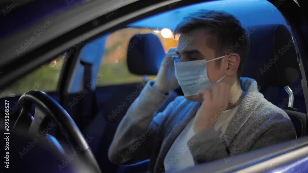 Happy businessman or taxi driver putting on medical face mask to prevent covid or coranavirus quarantine pandemic. Freelancer in a car after school in a face mask due to covid-19. Delivery service. Happy businessman or taxi driver putting on medical face mask to prevent covid or coranavirus quarantine pandemic. Freelancer in a car after school in a face mask due to covid-19. Delivery service.