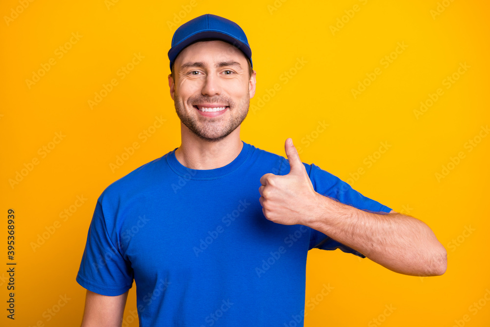 Photo of satisfied person toothy smile show thumb up wear blue cap isolated on vibrant yellow color background Photo of satisfied person toothy smile show thumb up wear blue cap isolated on vibrant yellow color background