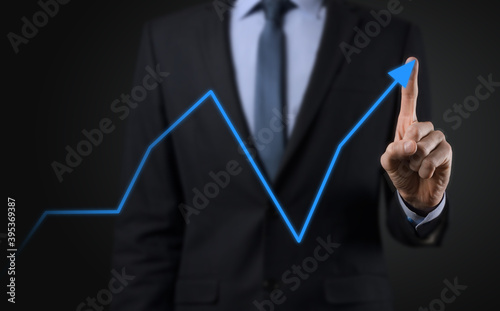 Businessman on a black background presses, presses a finger on a positive growth arrow. Graphs of indicators. Business development and finance concept