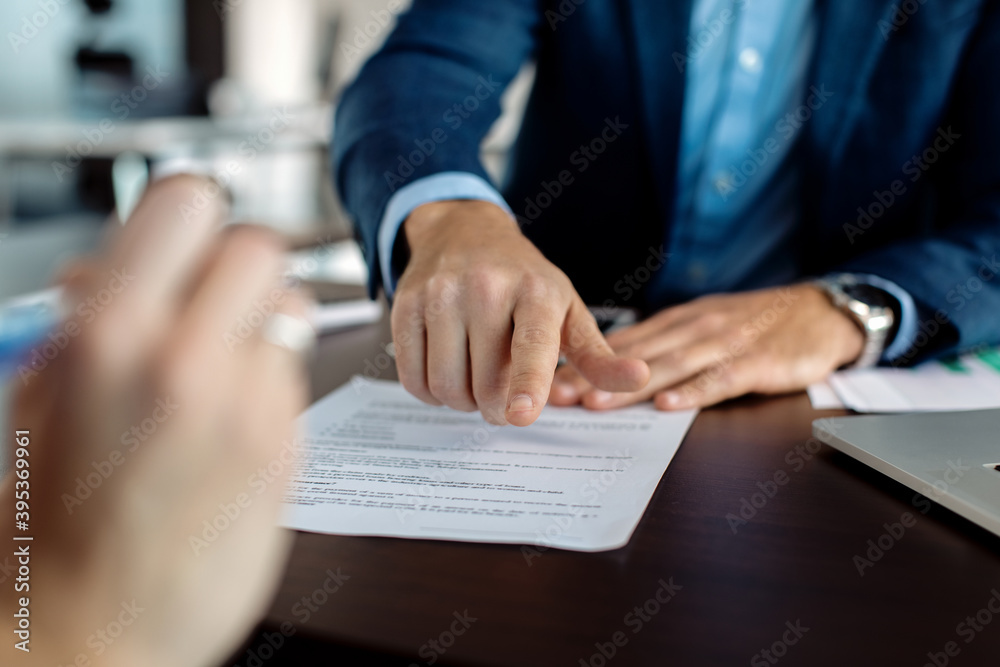 Close-up of financial advisor pointing at place of signature on a contract. Close-up of financial advisor pointing at place of signature on a contract.