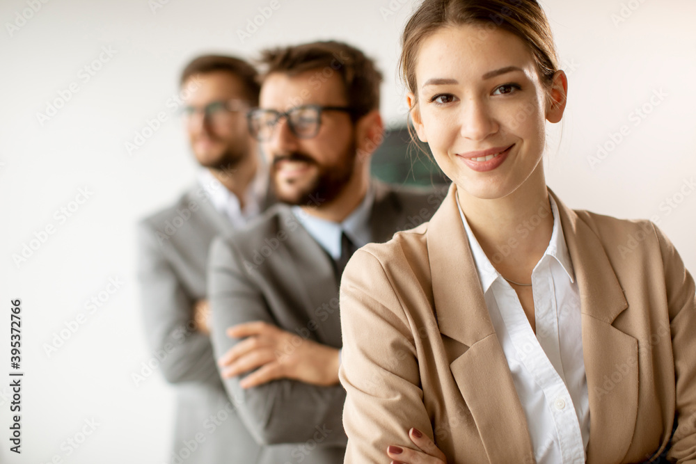 Smiling young business woman standing with group of corporate colleagues in a row together Smiling young business woman standing with group of corporate colleagues in a row together