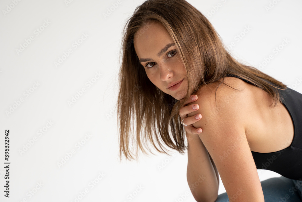 Portrait of young pensive caucasian woman posing in black underwear and blue jeans, sitting on old chair in white studio. Model tests of pretty girl in basic clothes on cyclorama. Portrait of young pensive caucasian woman posing in black underwear and blue jeans, sitting on old chair in white studio. Model tests of pretty girl in basic clothes on cyclorama.