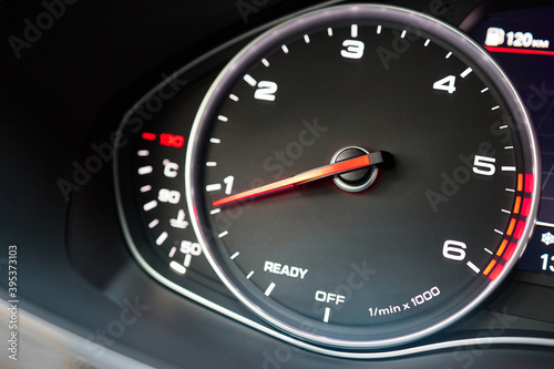 Rev counter of car selective focus closeup with copyspace.Tachometer or revolution counter, RPM gauge with red glowing needle on car dashboard with fuel and engine temperature indicators.