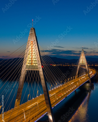 Budapest, Hungary - Aerial view of the beautiful illuminated Megyeri Bridge over River Danube at blue hour. 