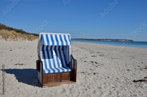 Traditional beach chair on a public beach on island Ruegen in Germany,Mecklenburg West Pomerania,Baltic sea, bay of county Thiessow on peninsula Moenchgut on a sunny day,chalk cliffs in the background