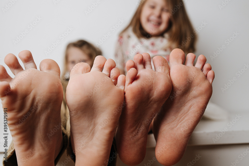 Foto de Children's bare feet close up to the camera. Their blurred giggling  faces in a background. do Stock | Adobe Stock