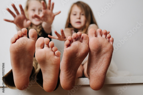 Brother and sister holding bare feet close up to the camera. Their blurred faces in a background. Hands reaching to camera. photo
