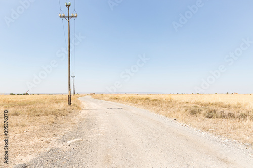 Los Monegros - a gravel road with electricity pylons parallel  to the N-II road next to Fraga on a summer day, province of Huesca, Aragon, Spain photo