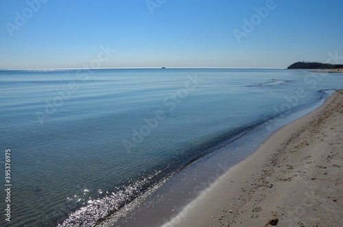 Island Ruegen in Germany  Mecklenburg West Pomerania  Baltic sea  the beach of the county Thiessow on peninsula Moenchgut on a sunny day in spring  ship on horizon reflections of sunlight in the water