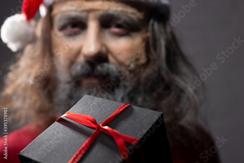 close-up portrait, santa giving christmas present on a grey background