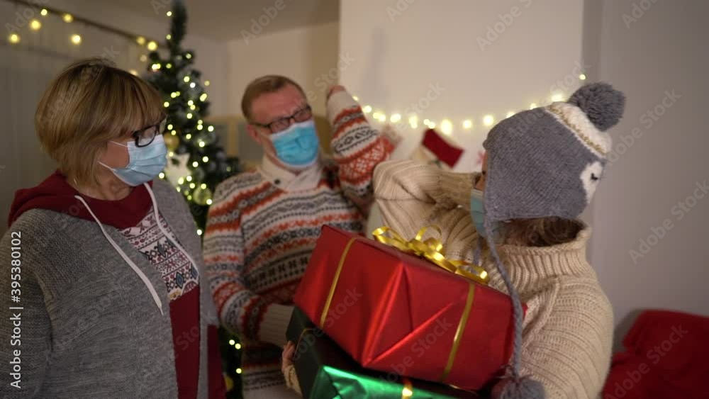 Christmas and covid-19. Contactless greeting. Mother, father and daughter wearing protective medical masks. Quarantine isolation social distance. New year holiday. Festive mood 2021during lockdown