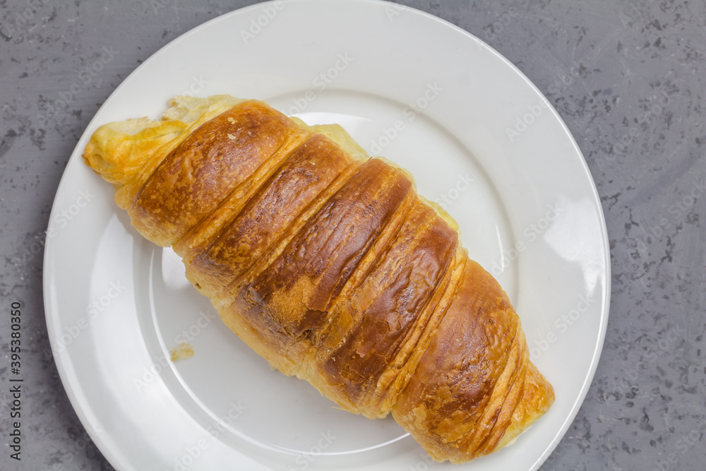 Croissant on white plate with copy space - top view close up photo