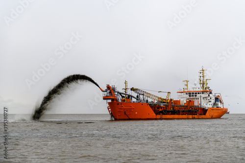 Vessel engaged in dredging. Dredger working at sea. Ship excavating material from a water environment. photo