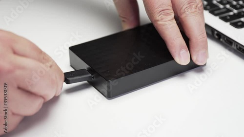 Connecting usb cable to a portable hard disk on white background