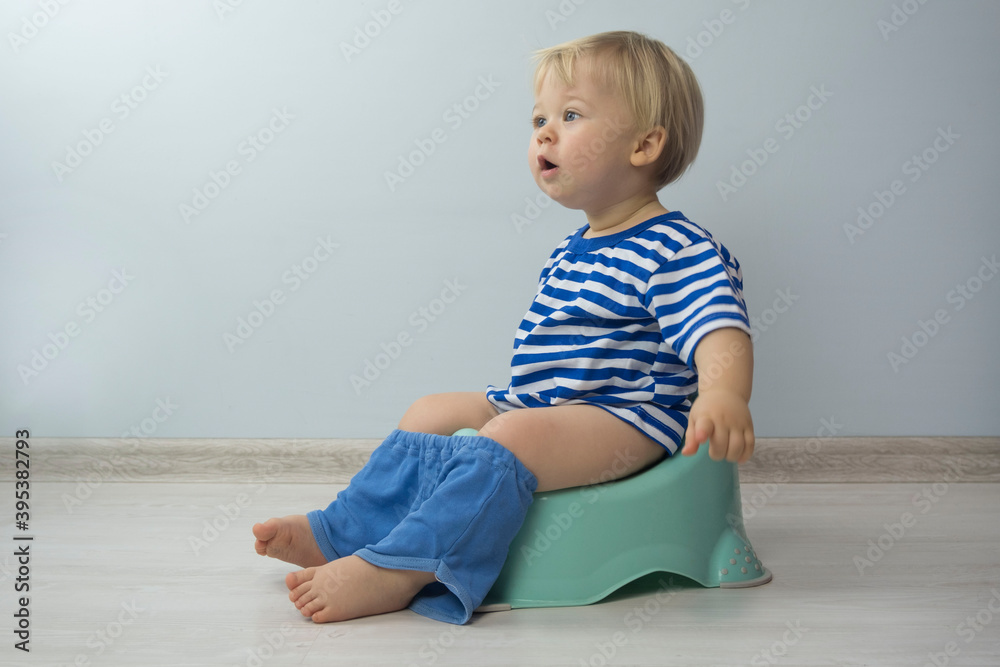 small Caucasian boy with blond hair and blue eyes is sitting on a child's toilet small Caucasian boy with blond hair and blue eyes is sitting on a child's toilet