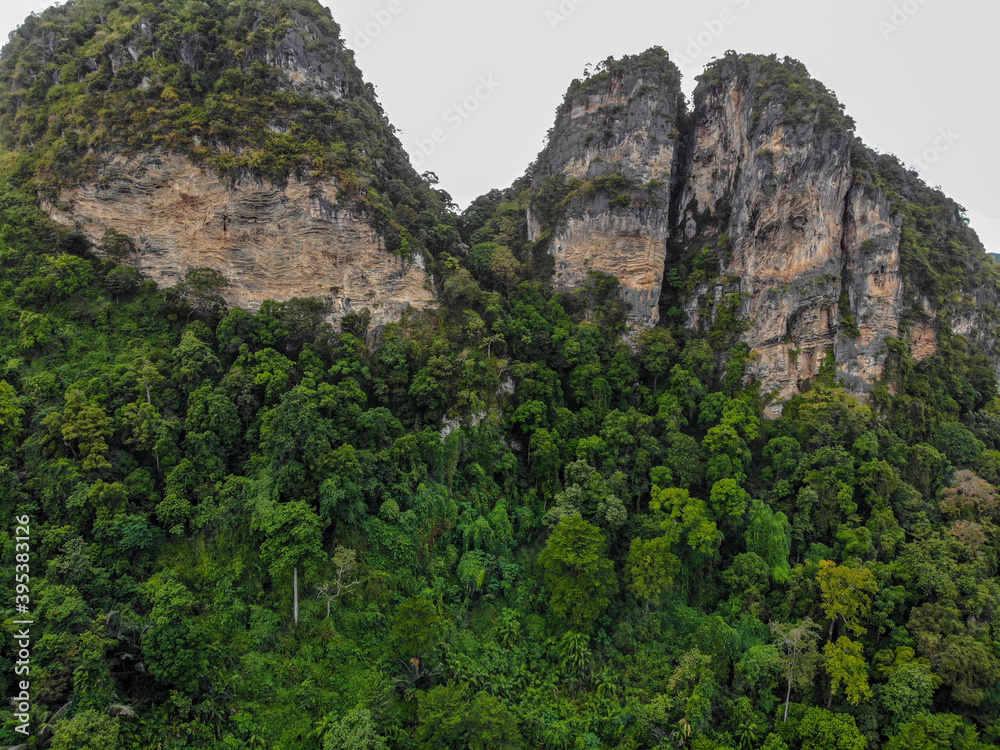 AERIAL: Breathtaking aerial view of the tall mountains covered by the tropical forest towering over the empty valley in the heart of exotic island.