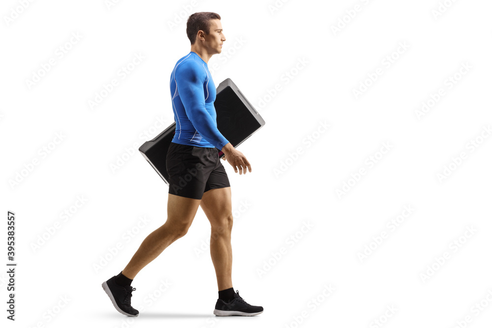 Full length profile shot of a fit man walking and carrying an aerobic stepper Full length profile shot of a fit man walking and carrying an aerobic stepper
