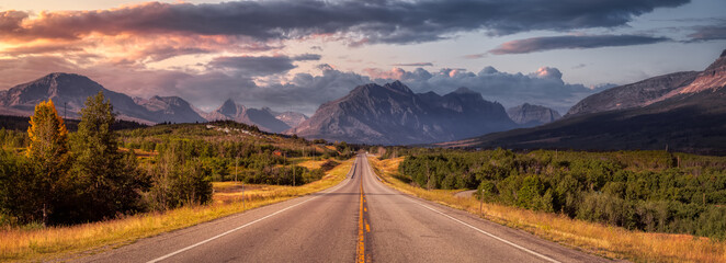 Beautiful View of Scenic Highway with American Rocky Mountain Landscape in the background. Colorful Summer Sunrise Sky. Taken in St Mary, Montana, United States.