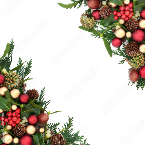 Traditional Christmas border with red & gold bauble decorations, holly & winter greenery on white background. Festive composition for the holiday season. Flat lay, top view, copy space.