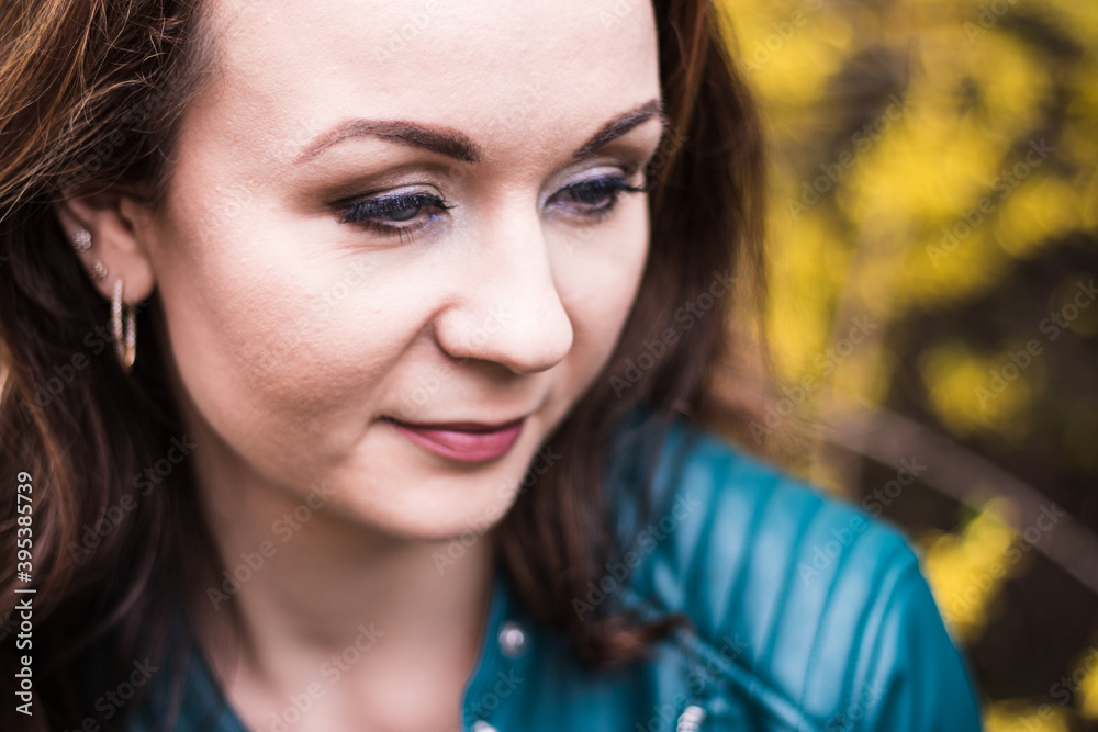 Portrait of a beautiful young woman. Looking at camera and smiling. Smart casual clothes, blurred urban background