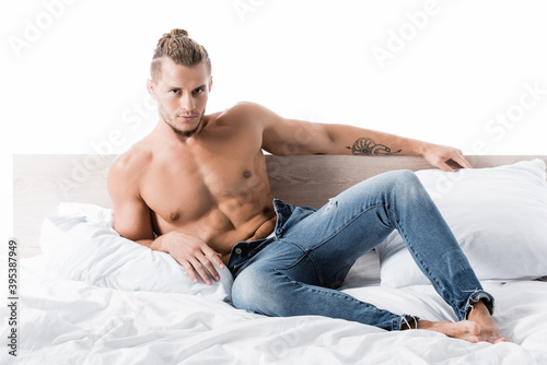  shirtless man in jeans posing in bed isolated on white