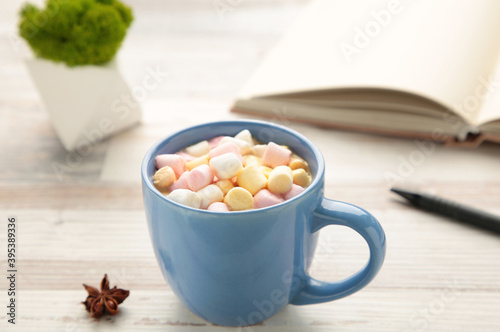 Cup of hot chocolate with marshmallow on grey wooden background.