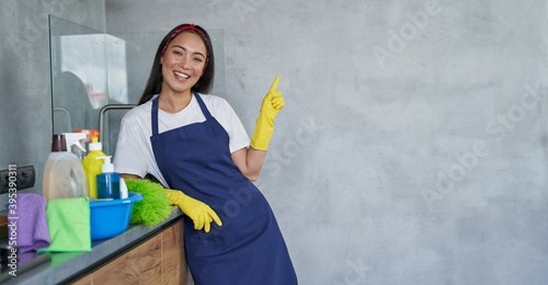 Принти на полотні Cheerful young woman, cleaning lady in protective gloves smiling at camera, poin
