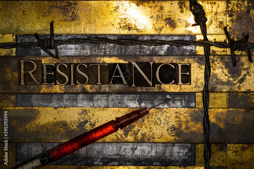 Resistance text message on textured lead grunge copper and vintage gold background with syringe filled with red fluid lined with barbed wire