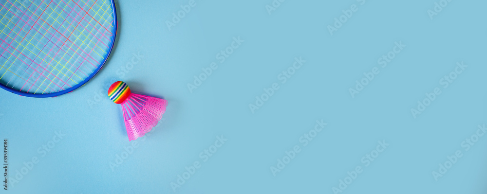 Pink badminton shuttlecock and racket on a blue background. Concept: minimalism, summer outdoor games