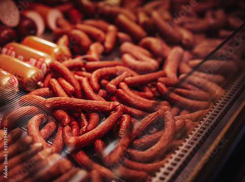 Counter full filled and neatly folded with raw and smoked meat and sausages in butcher shop.