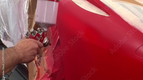carrozziere spruzza vernice rossa su un auto sportiva  photo