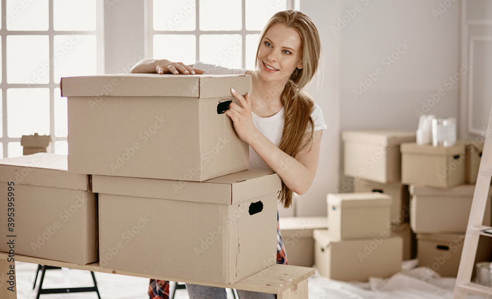 Fototapeta premium A beautiful single young woman unpacking boxes and moving into a new home