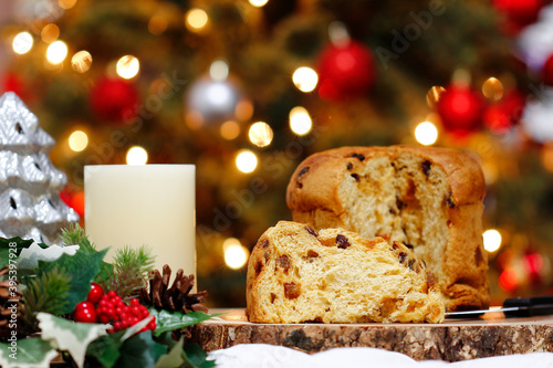 Panettone on a board with Merry Christmas tree, lights and a candle