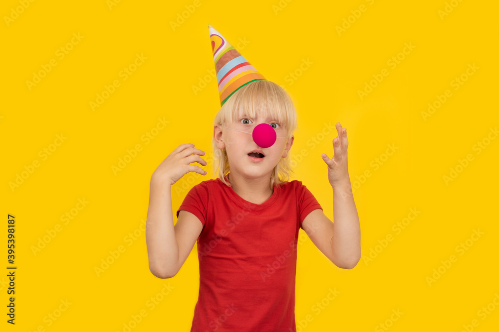 Surprised boy in clown outfit on yellow background. Childrens holiday Surprised boy in clown outfit on yellow background. Childrens holiday