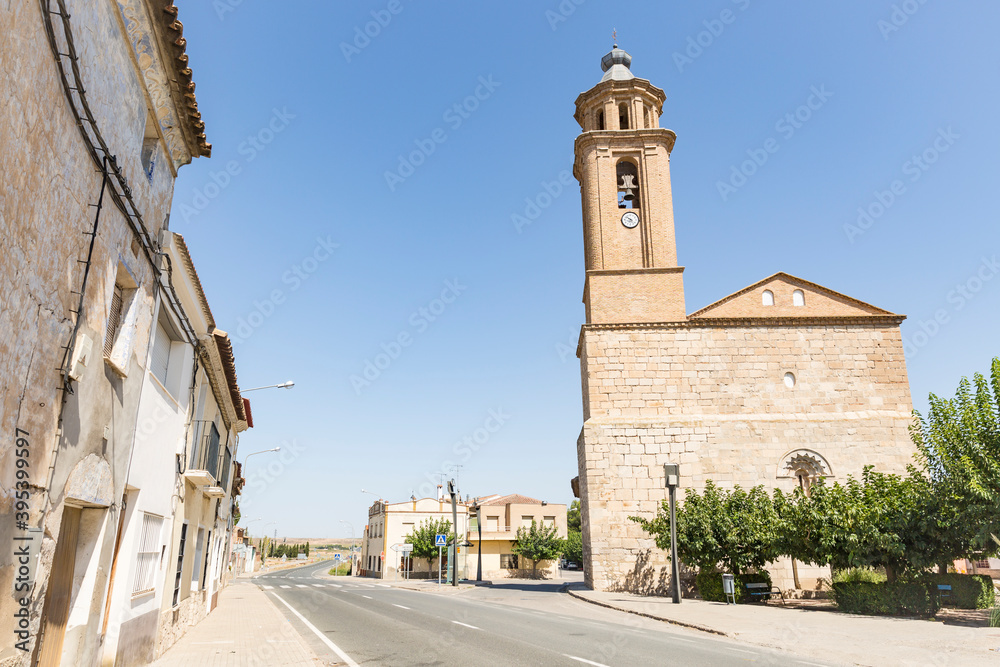 a paved road passing through Candasnos town with Our Lady of the Assumption church in the foreground, province of Huesca, Aragon, Spain