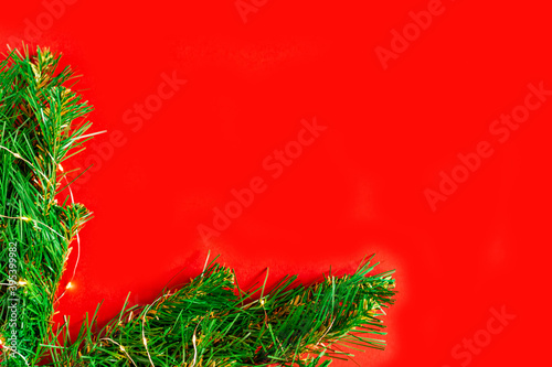 green pine branches with light bulbs on a red background frame the corner of the Christmas background, holiday lights,