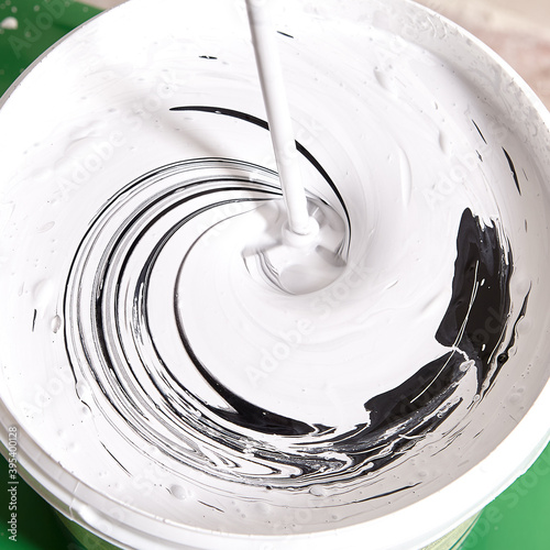 Handyman makes gray color while mixes black and white using drill. photo