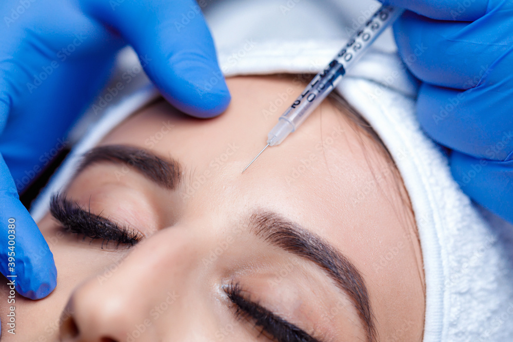 Beautiful woman getting lifting injection in forehead. Close-up woman hyaluronic acid injection. Botox Injections of skin rejuvenation. Cosmetic procedures, botox injections, hyaluronic acid.