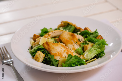 Plato de ensalada fresca con lechuga, pollo, queso y semillas frescas emplatado sobre mesa
