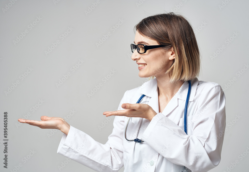 female nurse in a medical gown gesturing with her hands on a light background