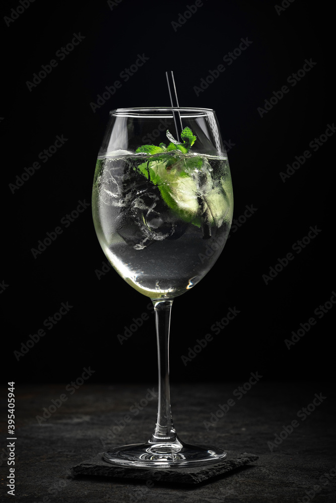 Hugo cocktail with Prosecco, lime, ice, mint and Melissa syrup on a stone background, aperitif drink